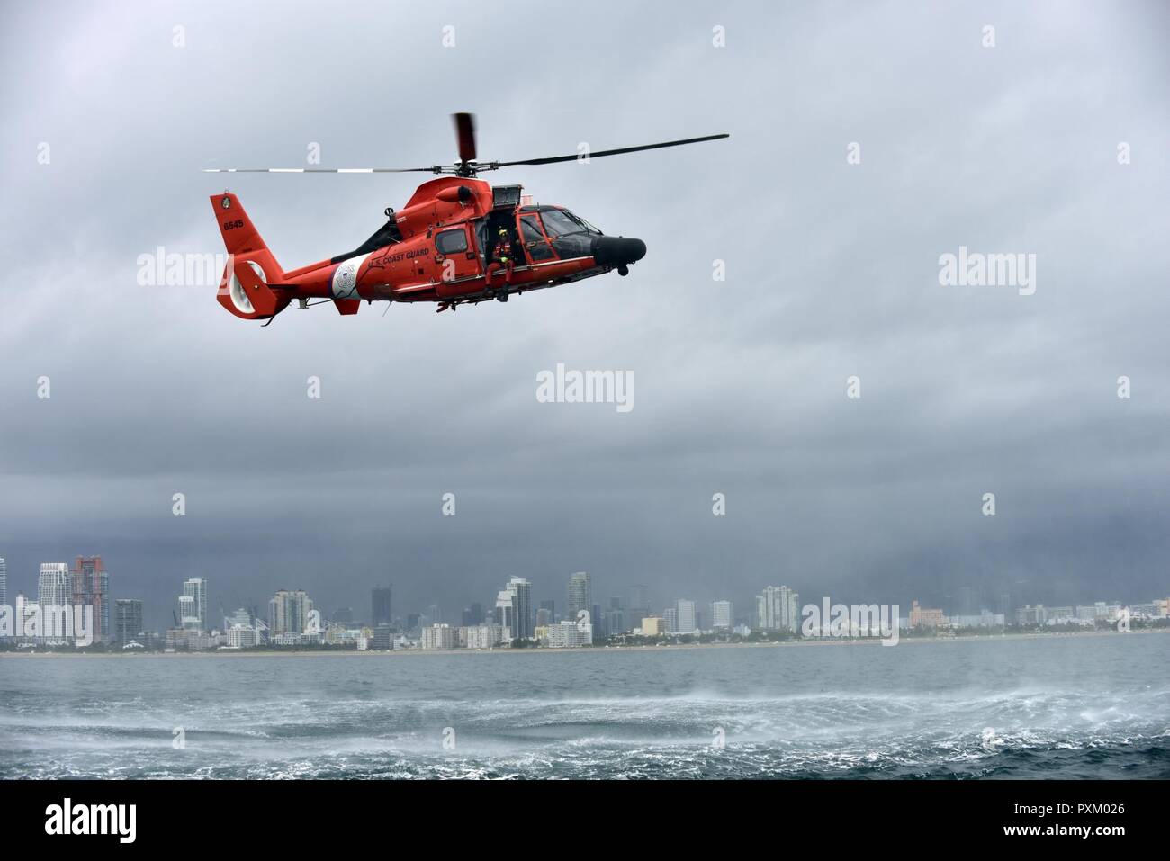 3ª clase suboficiales Bryan Evans, la estación aérea de la Guardia Costera Miami nadador de rescate, se prepara para una implementación de caída libre desde un helicóptero MH-65 Dolphin este de Miami Beach el 6 de junio de 2017. (Coast Guard Foto de stock
