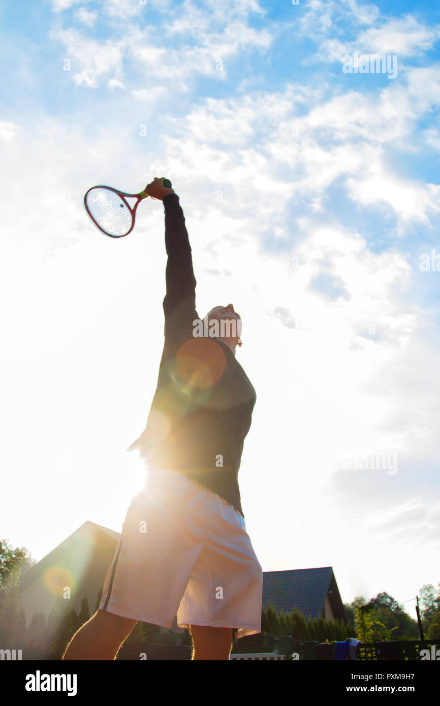 Tenista profesional jugando un partido de tenis en una cancha. Él está a punto de golpear la bola con la raqueta. Foto de stock