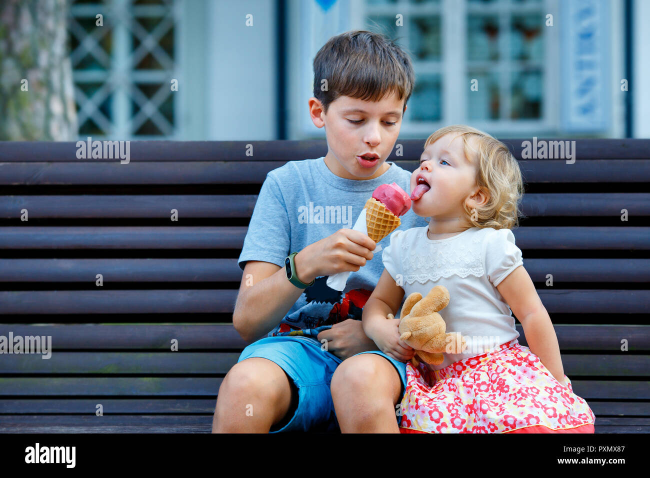 Gran hermano dando su helado a hermana pequeña piscina Foto de stock