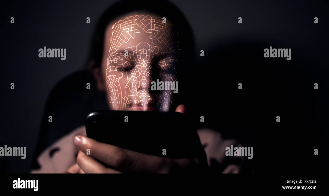 Joven sosteniendo su teléfono inteligente y mediante el reconocimiento facial para desbloquear el dispositivo Foto de stock