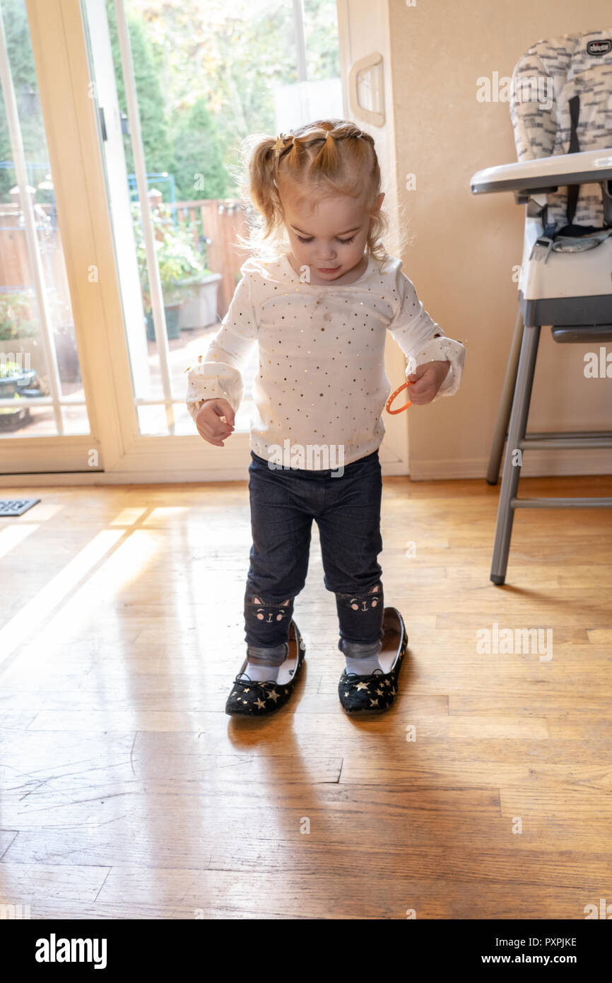 Casi 2 años de edad, niña tratando de caminar en zapatos de su stock - Alamy