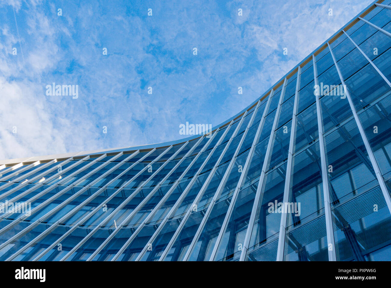 Fachada de vidrio curvo moderno edificio con fondo de cielo azul. Foto de stock