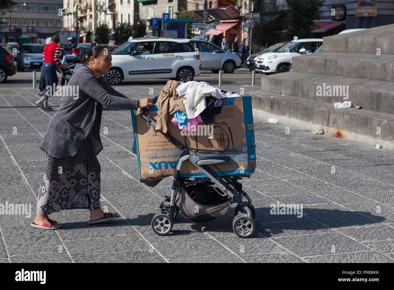 A migrantes desamparados empuja sus pertenencias por las calles de la ciudad de Nápoles, Italia Foto de stock