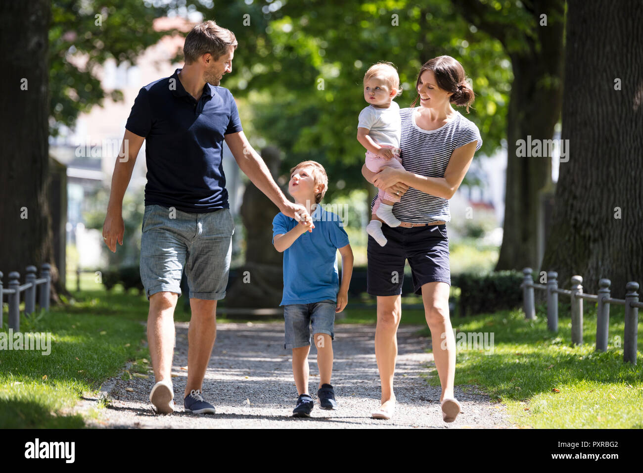 Feliz familia con dos niños caminando en el parque Foto de stock