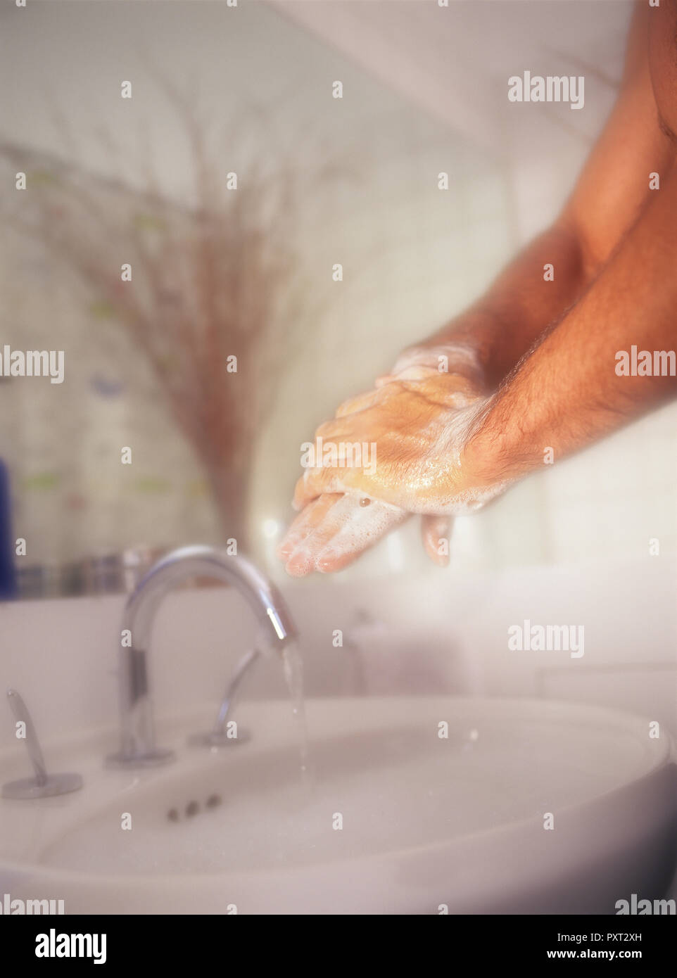 Hombre fregado y lavado de las manos con vigor contra un fondo suave en el baño. Foto de stock