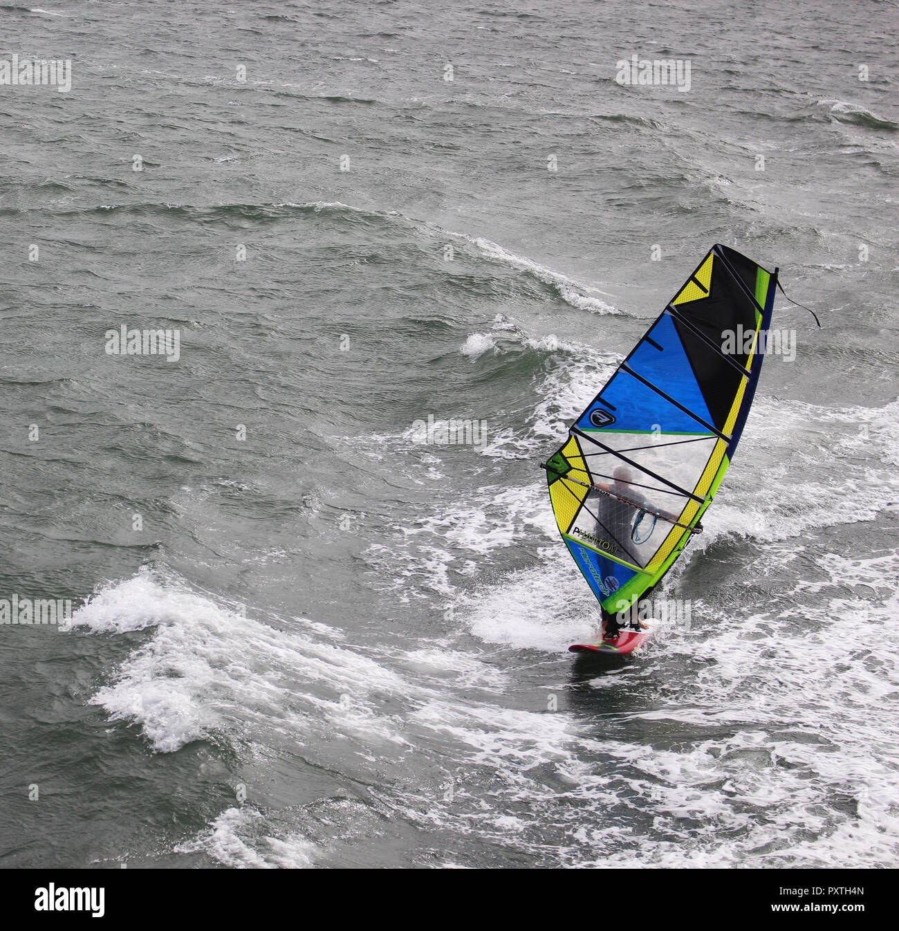 Una tabla de windsurf y su azul, amarillo y negro Sail Surf durante un
