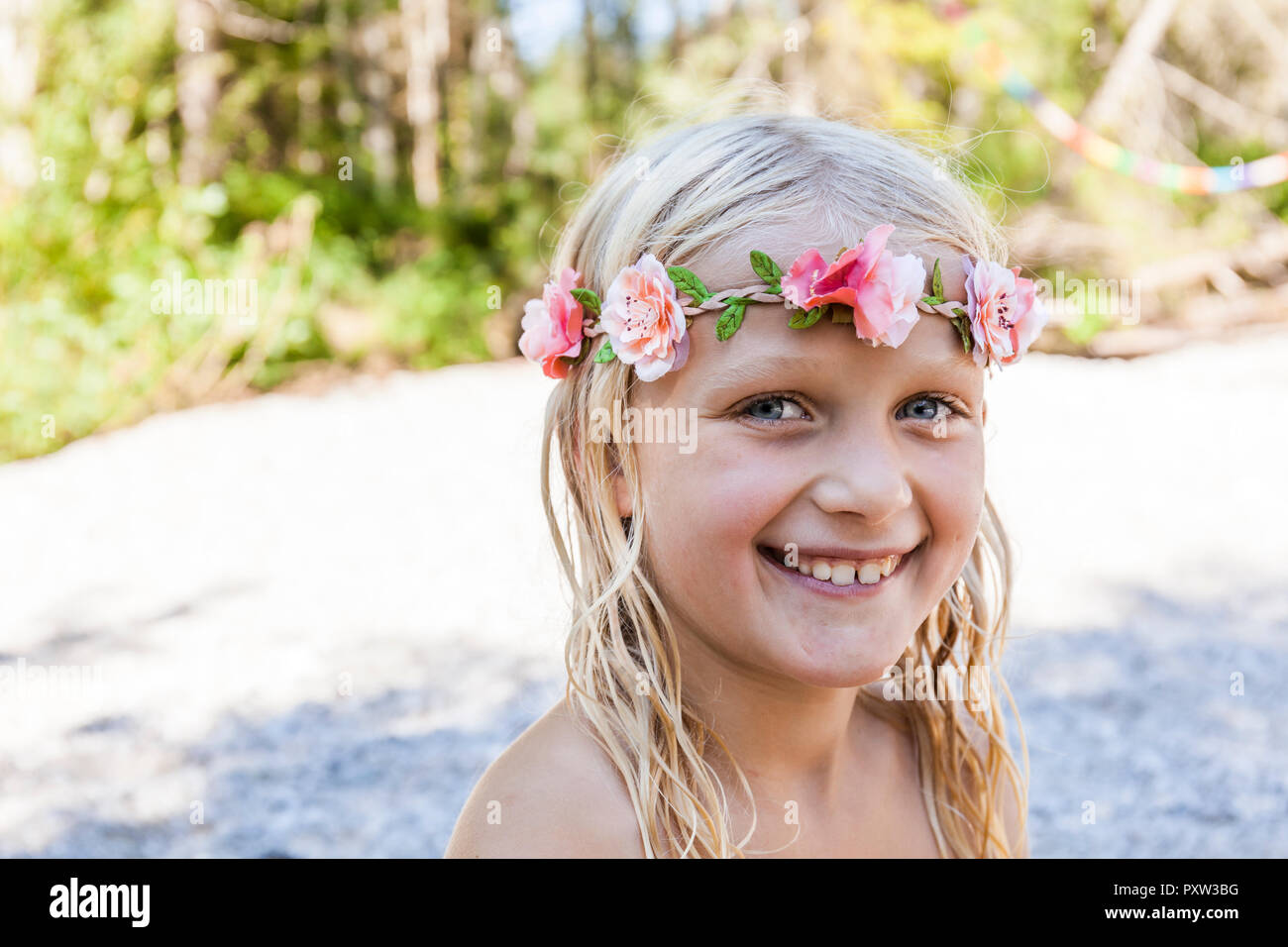 Retrato de niña alegre portando corona de flores al aire libre en verano Foto de stock