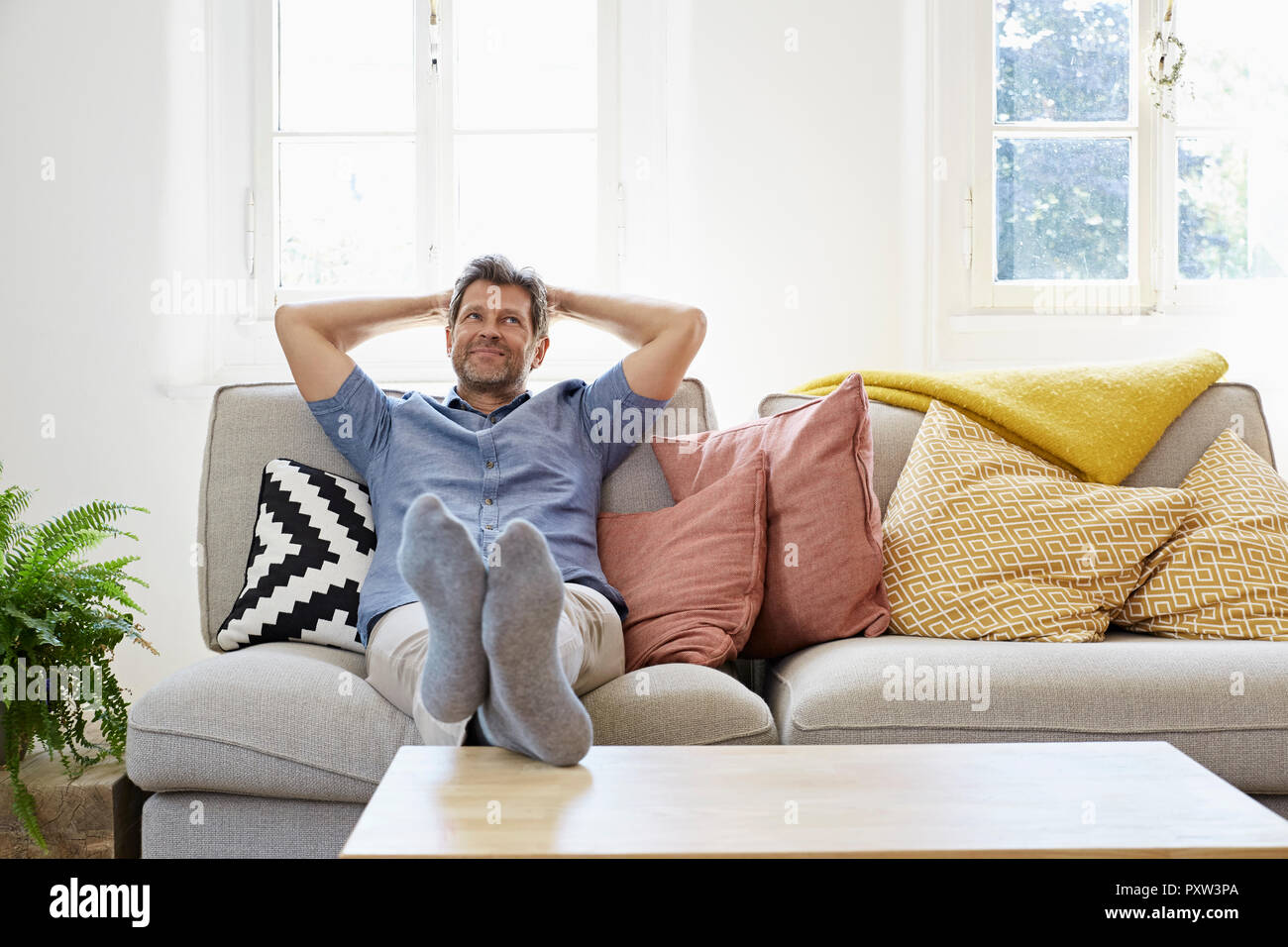 Hombre sentado en el sofá en casa, relajante Fotografía de stock - Alamy