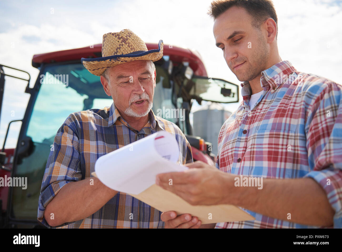 Dos agricultores discuten los datos desde el portapapeles en la granja Foto de stock