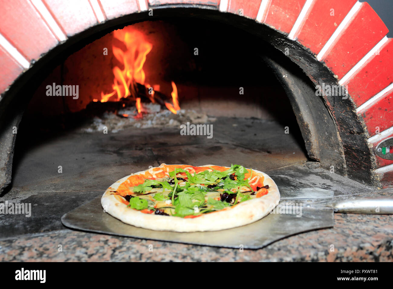Aceitunas negras, jamón, salchicha italiana, cohete frescas y virutas de  parmesano Pizza, cocinado en un horno de leña para pizza tradicional  Fotografía de stock - Alamy