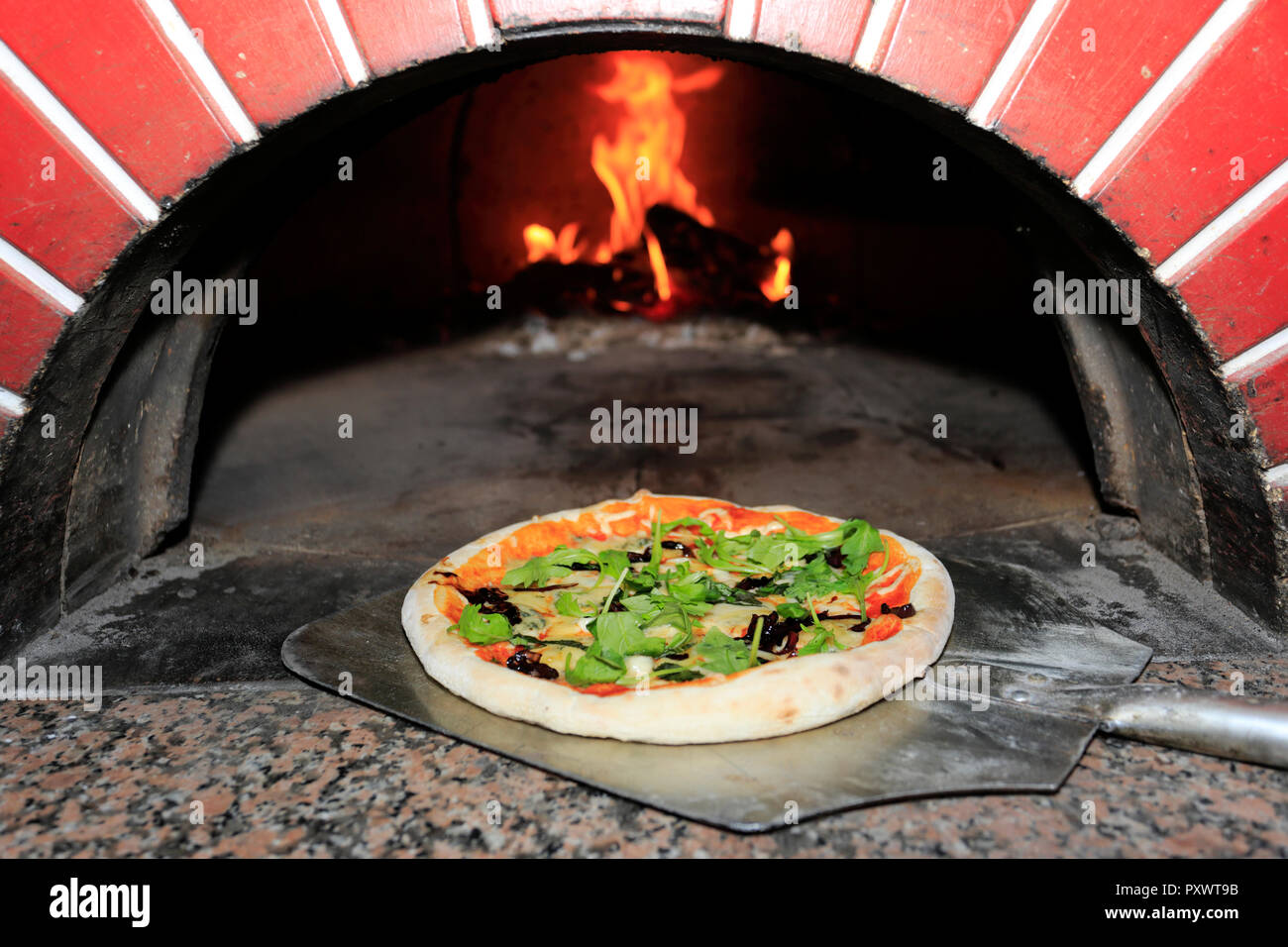 Aceitunas negras, jamón, salchicha italiana, cohete frescas y virutas de  parmesano Pizza, cocinado en un horno de leña para pizza tradicional  Fotografía de stock - Alamy