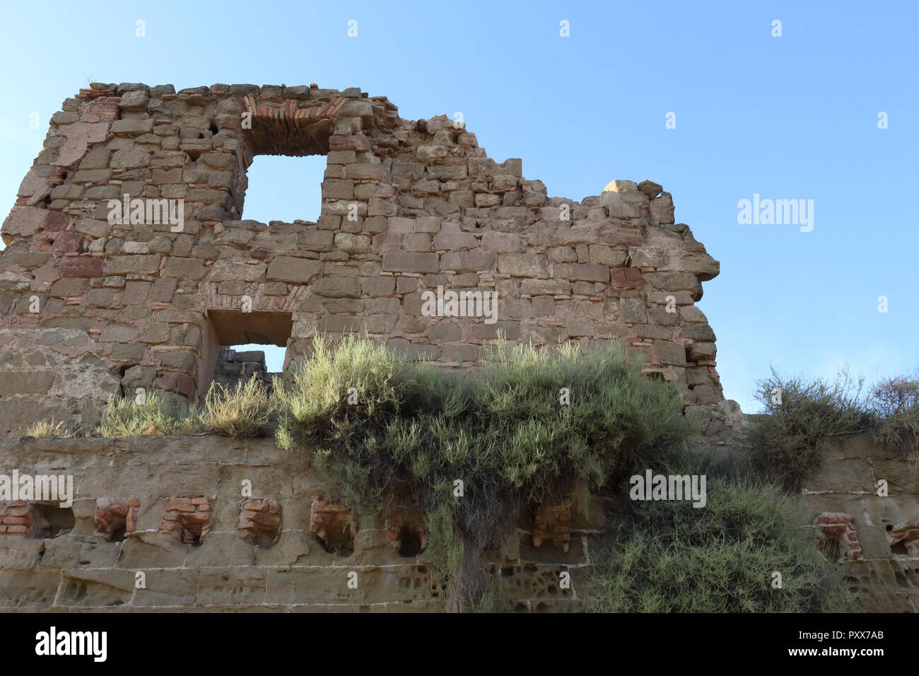 El amarillo erosionadas paredes del castillo de Montearagon abandonados en la región de Aragón, España, contra un cielo azul profundo durante un día de verano Foto de stock
