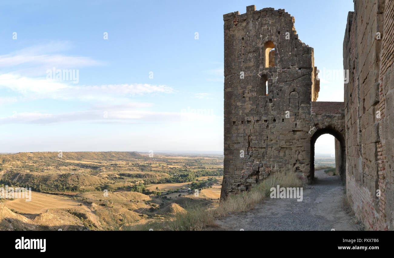 La torre con un arco sobre una calle de la ciudad medieval castillo de Montearagon abandonados, junto a campos de cultivo, labrados en verano, en Aragón, España Foto de stock