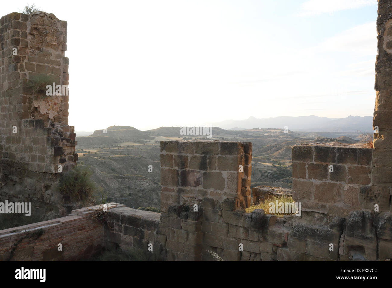 El labrado de los campos de cultivo de la región de Aragón visto desde las ruinas de los muros de defensa de piedra abandonados Montearagon castillo, durante la puesta de sol, en España Foto de stock