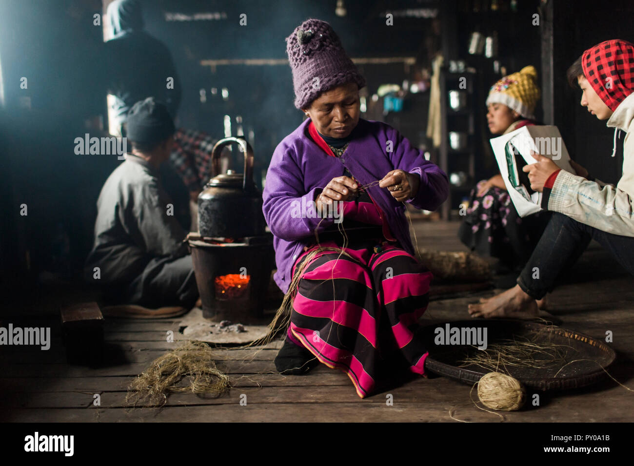 Anciana vistiendo knit hat tejiendo en el interior de la pequeña casa rural, Shan de Myanmar Myanmar Foto de stock