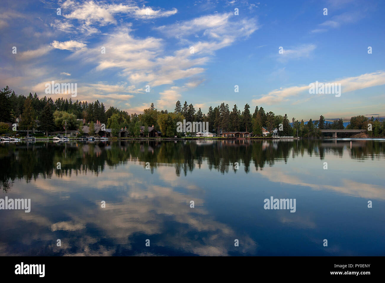 Lodges y los árboles se reflejan en el agua clara del lago Flathead, Montana, EE.UU. Foto de stock