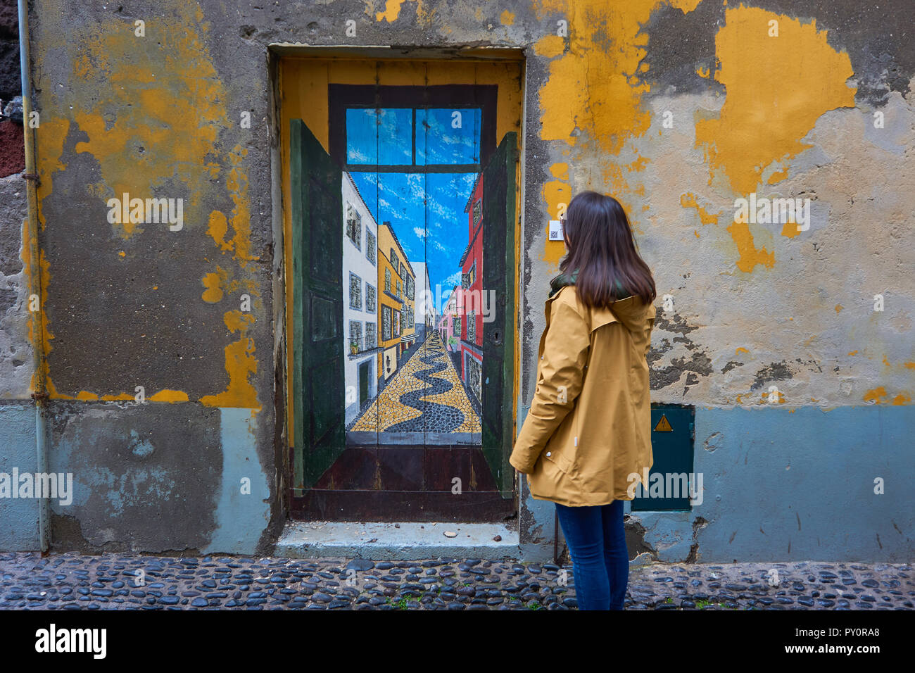 Mujer joven viajero mirando una puerta pintada en una calle tradicional en Funchal, Madeira Foto de stock