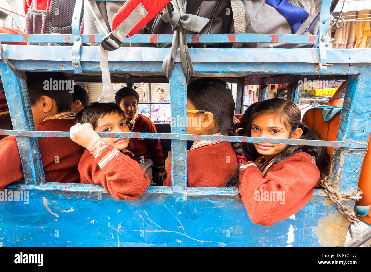 Jóvenes de clase media de niños indios fueron transportados a la escuela en un pequeño carro de ruedas tirado por un hombre Foto de stock