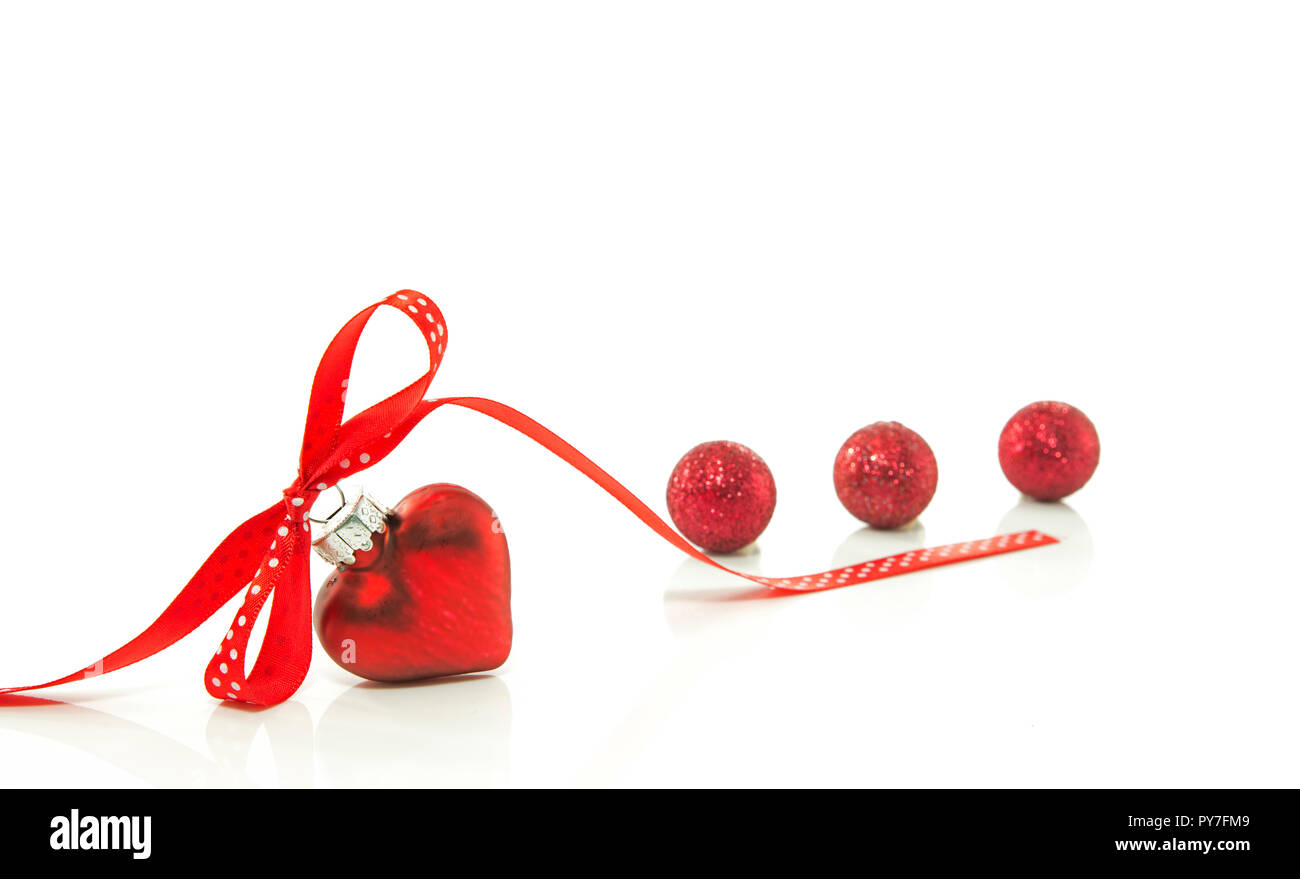 Corazón rojo para la Navidad con un arco de una cinta roja aislado sobre la cinta blanca Foto de stock