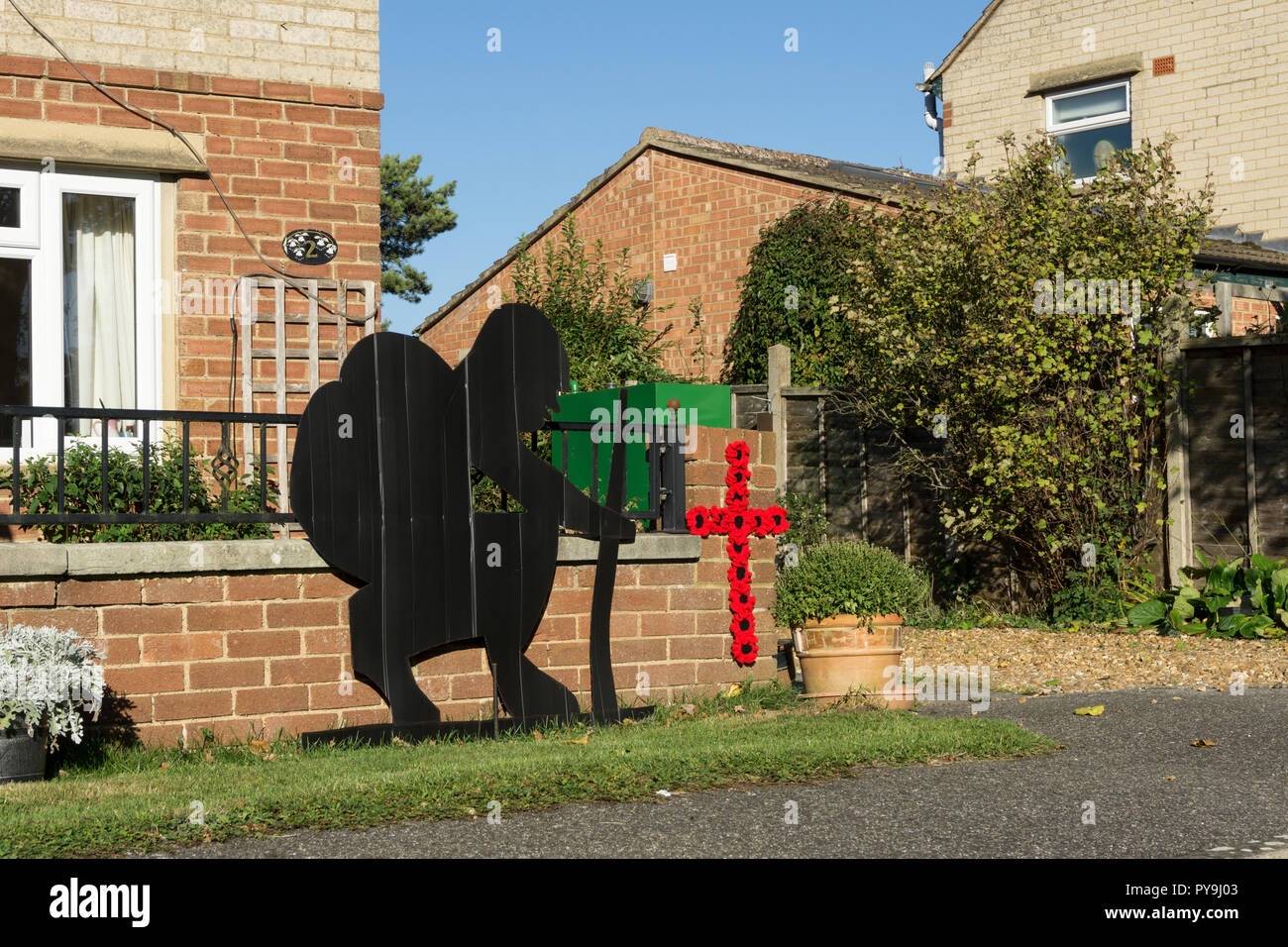 Soldado silueta y amapolas en la forma de una cruz fuera de una casa en la aldea de Quinton, Northamptonshire, Reino Unido Foto de stock