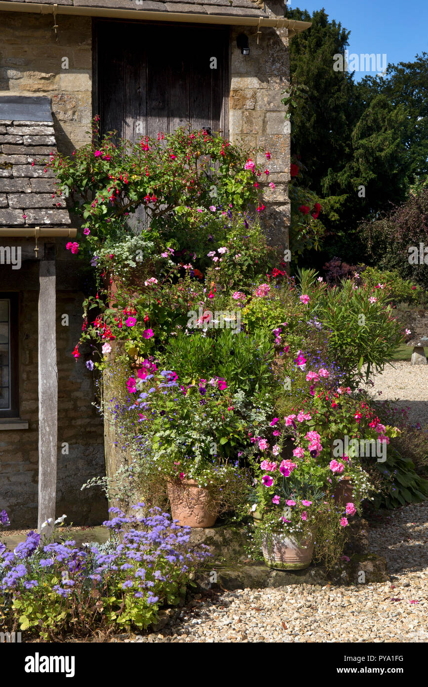 Ollas y jarrones de flores de verano en escalones de piedra de Cotswold cottage Jardín Inglés,Inglaterra,Europa Foto de stock
