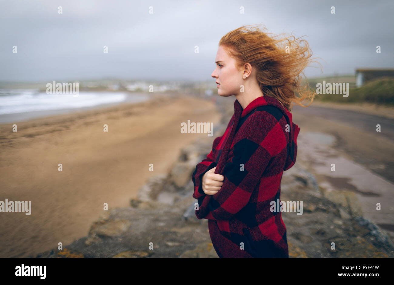 Pelirroja Mujer de pie con los brazos cruzados en la playa Foto de stock