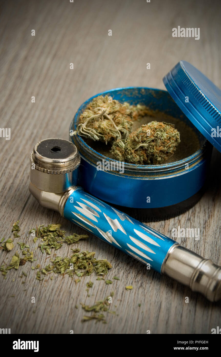 La marihuana y el tubo azul sobre fondo azul Molinillo de madera Foto de stock
