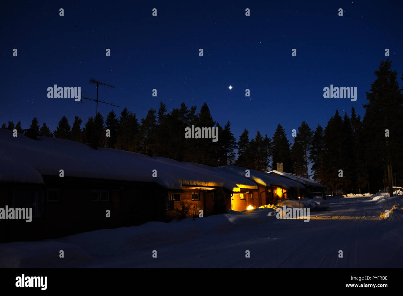 Casa adosada en invierno con nieve de noche. Planeta Venus y las Pléyades en el cielo estrellado. Foto de stock