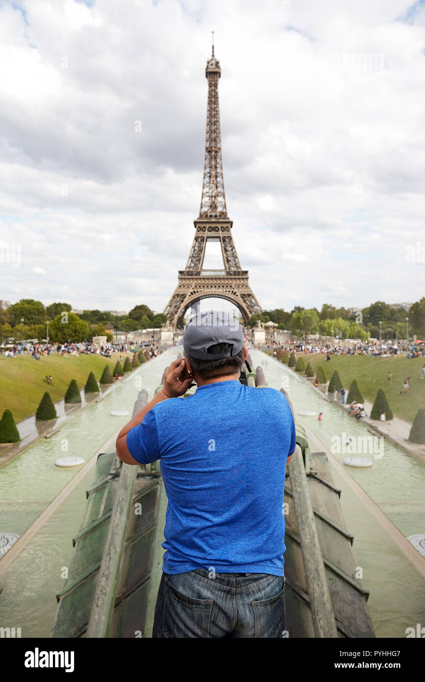 Paris, Ile-de-France, Francia - un hombre con un teléfono móvil en la oreja izquierda sobresale por encima de la fuente en el Jardins du Trocadero con la Torre Eiffel en el fondo. Foto de stock