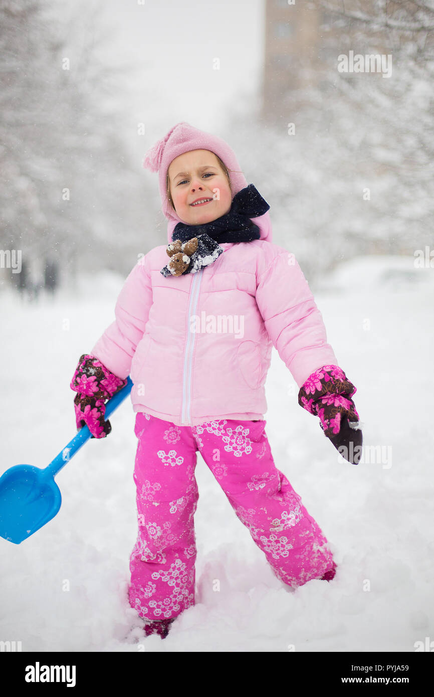 El niño juega con la nieve en el invierno. Una niña en una chaqueta y gorro  de punto brillante, atrapa a los copos de nieve en Winter Park para Navidad  Fotografía de