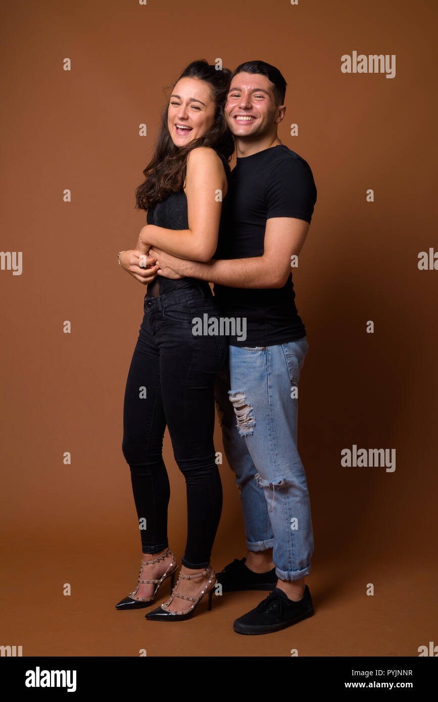 Pareja joven juntos y en el amor contra el fondo marrón Foto de stock