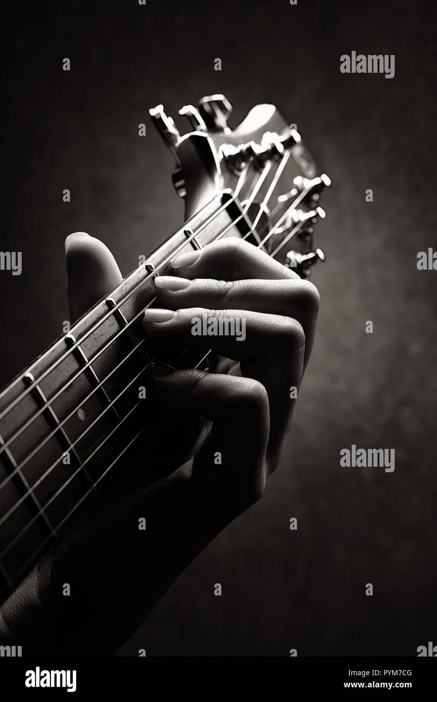 Mano de un guitarrista cercano con sólo el cuello y la cabeza de la guitarra en la imagen Foto de stock