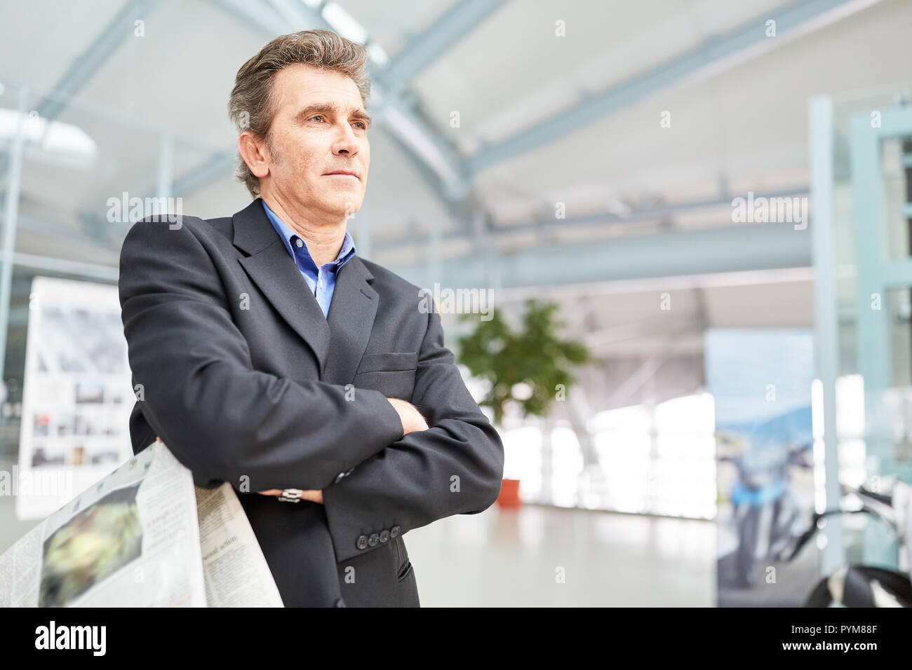 El hombre como un manager espera con los brazos cruzados en la terminal del aeropuerto o estación de tren Foto de stock