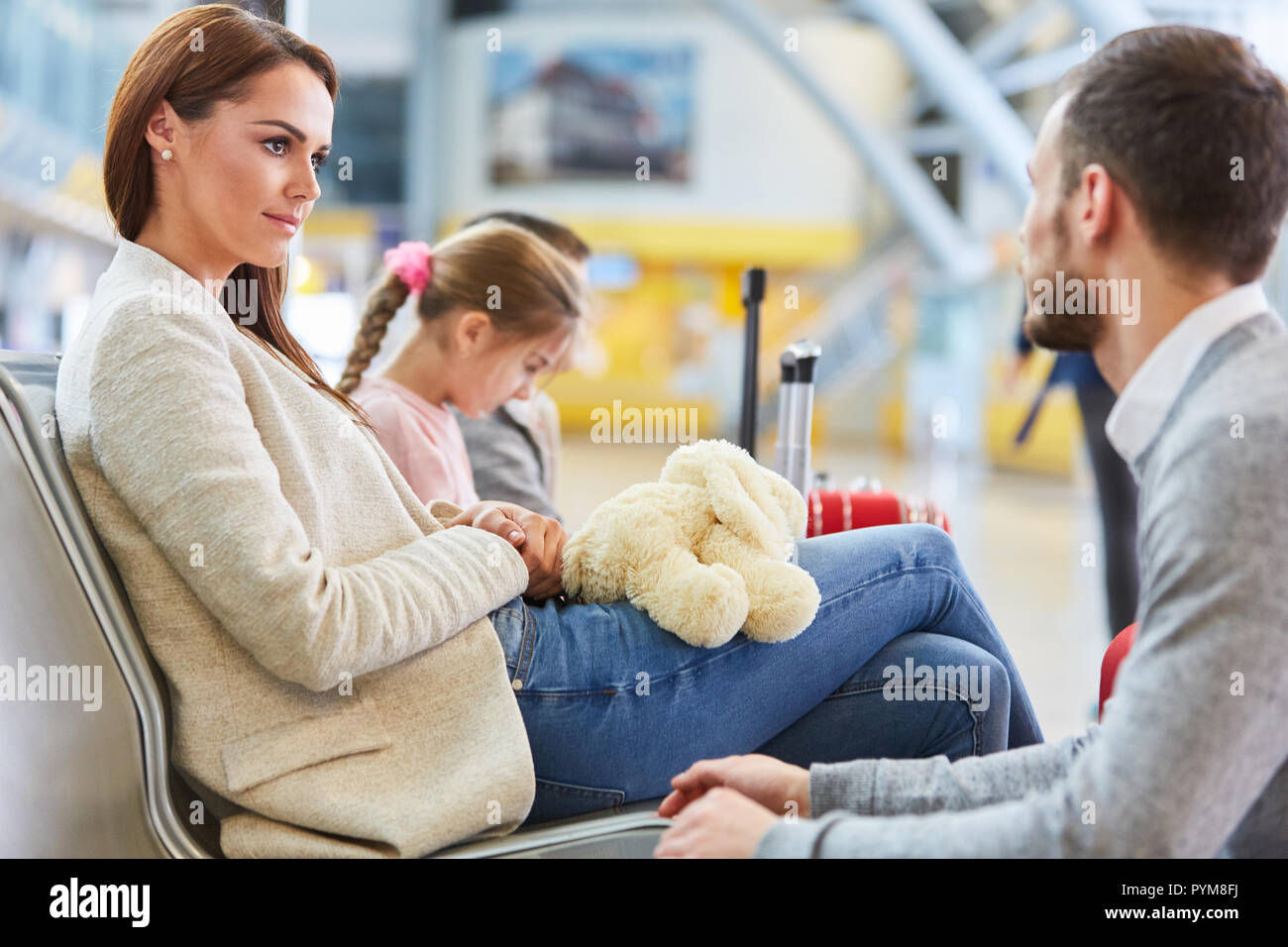 Familia y dos hijos están esperando en la zona de descanso para la salida de la terminal del aeropuerto Foto de stock