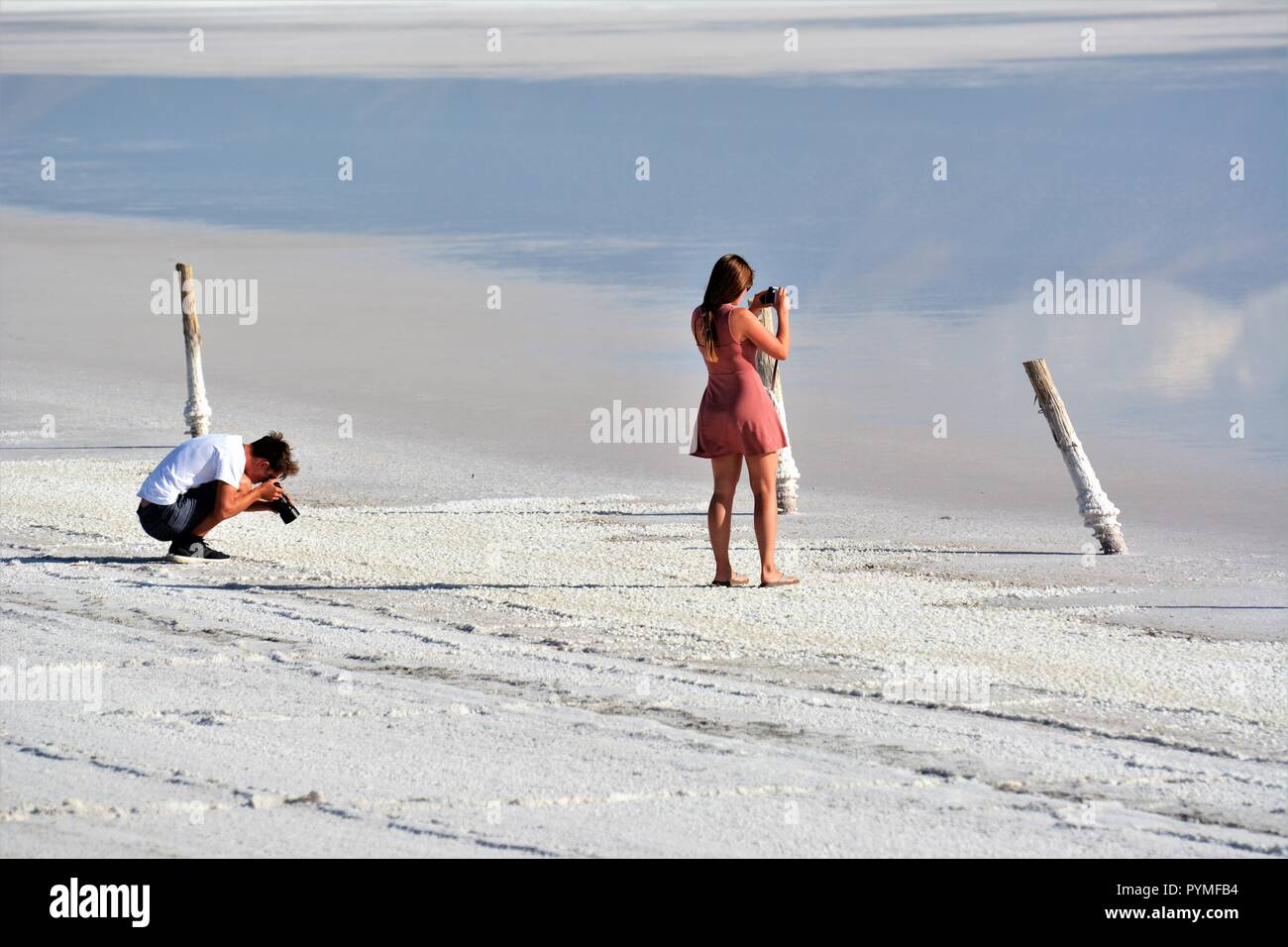 Pareja joven haciendo selfies y fotos en el Gran Lago Salado de Utah en los Estados Unidos USA en vacaciones en Waters Edge con DSLR y cámara de teléfono celular Foto de stock