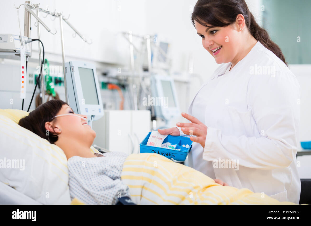 Médico en la unidad de cuidados intensivos del hospital hablando con paciente Foto de stock