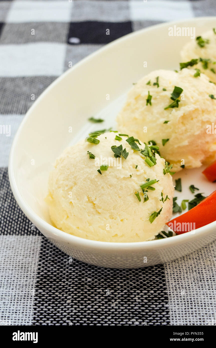 Kaymak sobre una placa blanca con los tomates y el perejil en un mantel cuadriculado Foto de stock