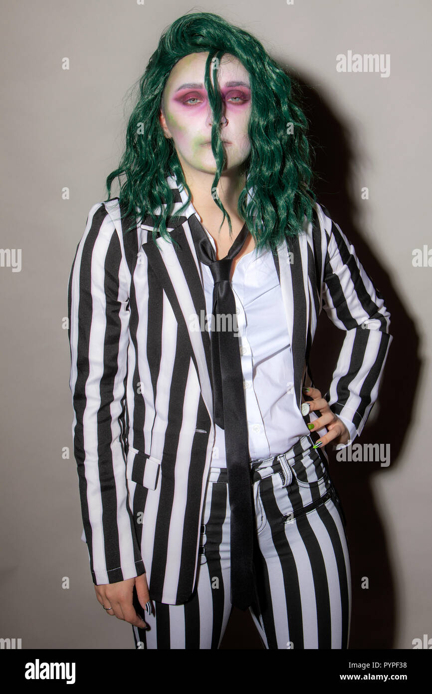 Una mujer joven se viste de fiesta de Halloween en un traje de rayas y el pelo  verde Fotografía de stock - Alamy