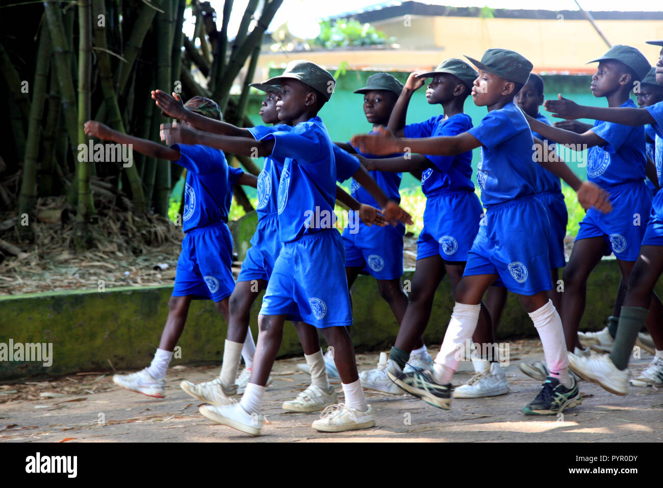 Los niños de la escuela práctica marchando bajo arcos de bambú en frente de los Jardines Botánicos de Bingerville cerca de Abidjan, Côte d'Ivoire Foto de stock