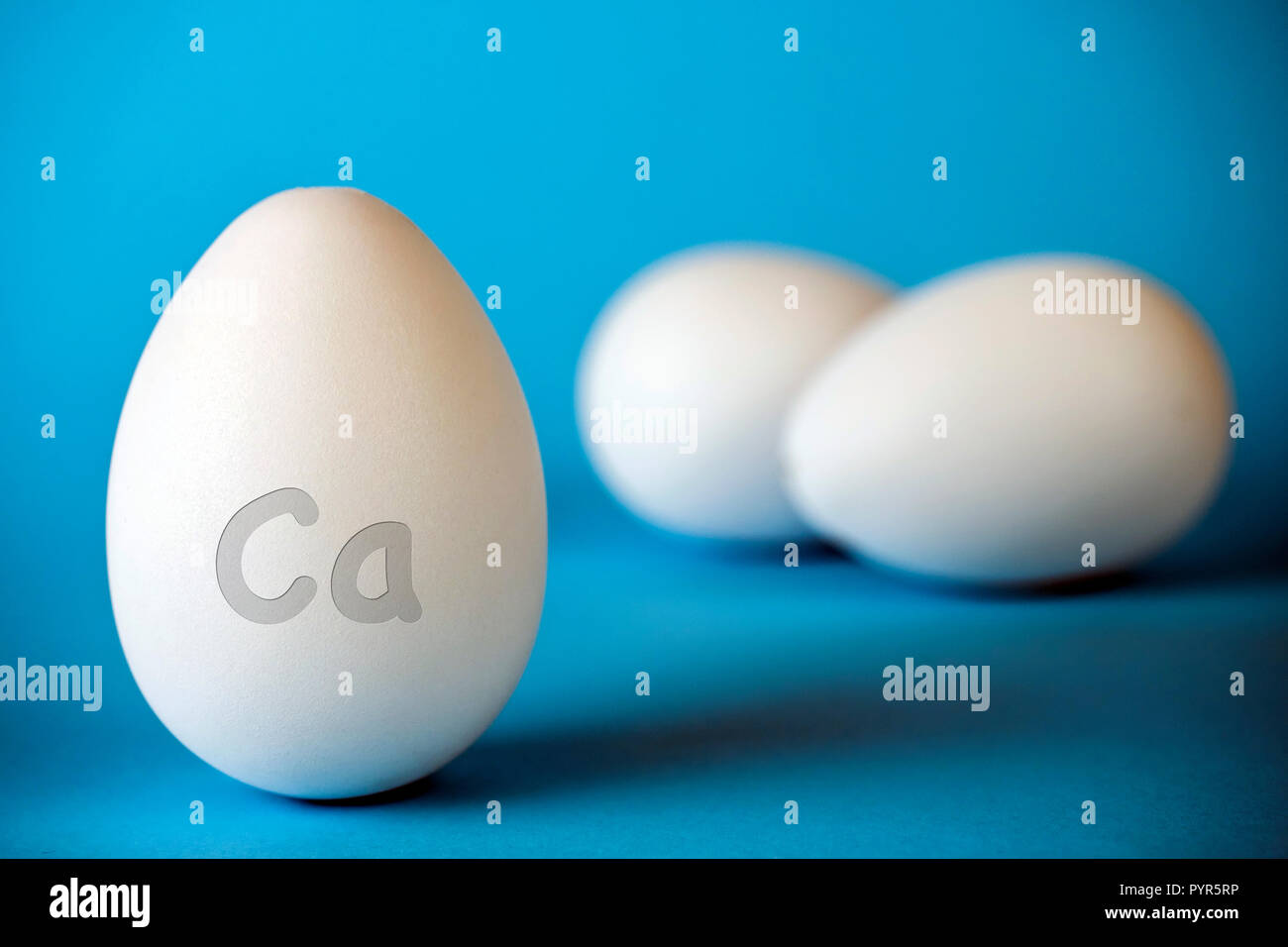 Los huevos de gallina han CA calcio para fortalecer los huesos, aislado en fondo azul. Foto de stock