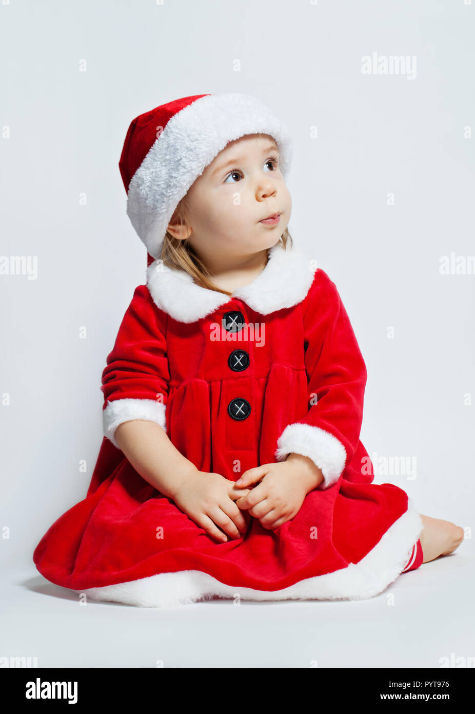 Navidad niño niña en Santa hat mirando hacia arriba sobre fondo blanco. Foto de stock