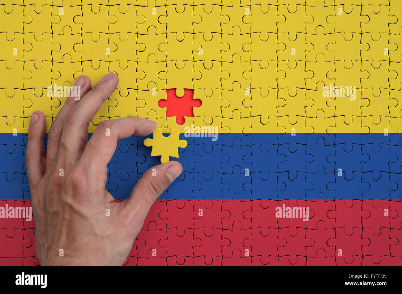 Bandera de Colombia es representado en un puzzle, que la mano del hombre  completa para plegar Fotografía de stock - Alamy