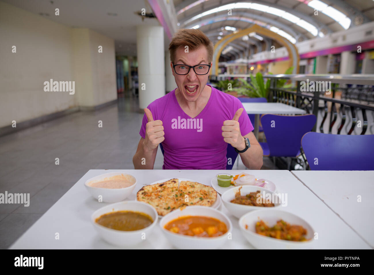 Joven apuesto hombre turístico disfrutando de la cocina india en el restaurante Foto de stock