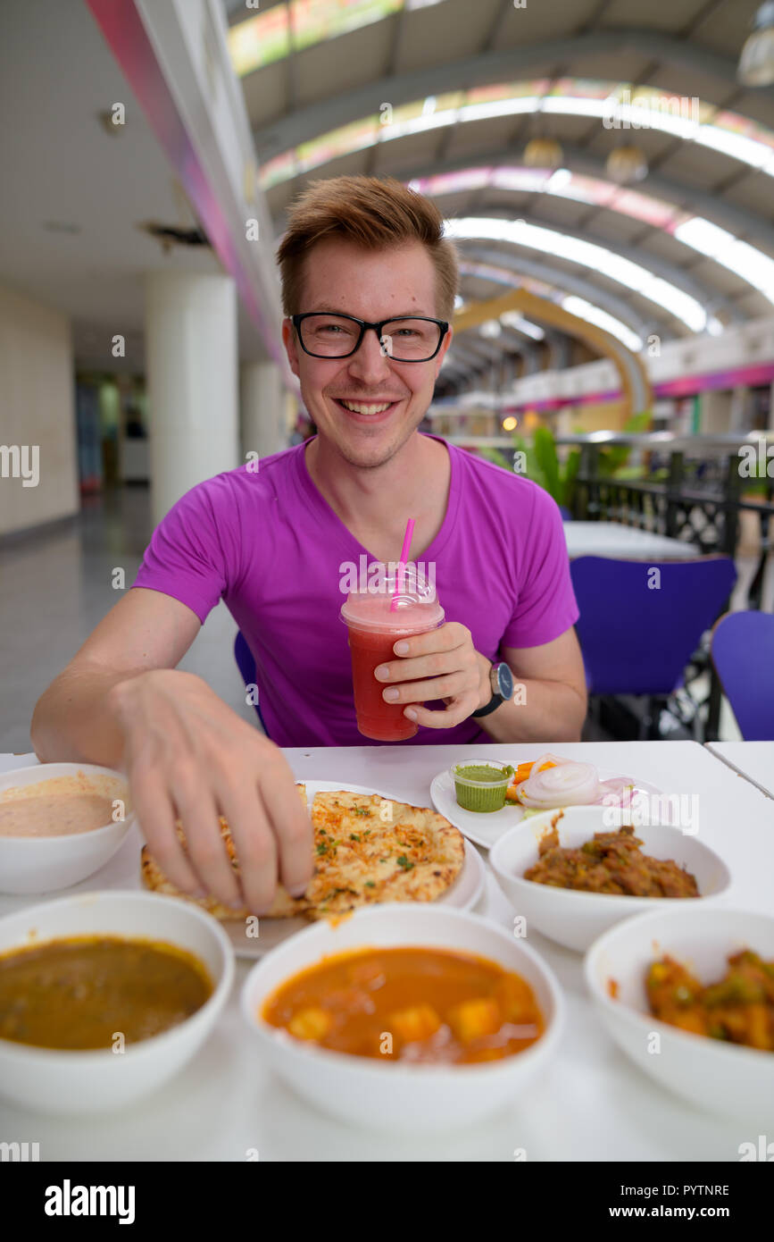 Joven apuesto hombre turístico disfrutando de la cocina india en el restaurante Foto de stock