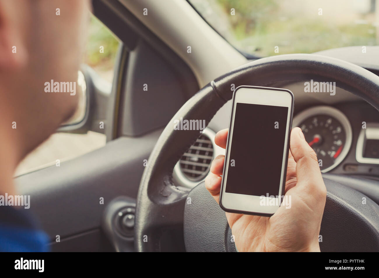 Hombre utilizando el smartphone en el coche, conductor titular del teléfono móvil con pantalla en blanco vacío. Foto de stock