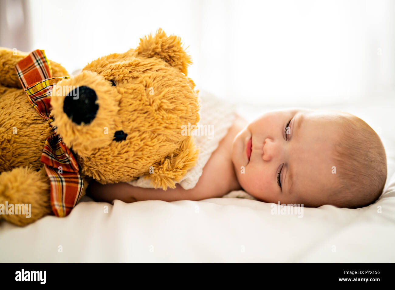 Pequeño bebé recién nacido niño, durmiendo con osito de peluche en casa en  la cama, descansando con juguete infantil Fotografía de stock - Alamy