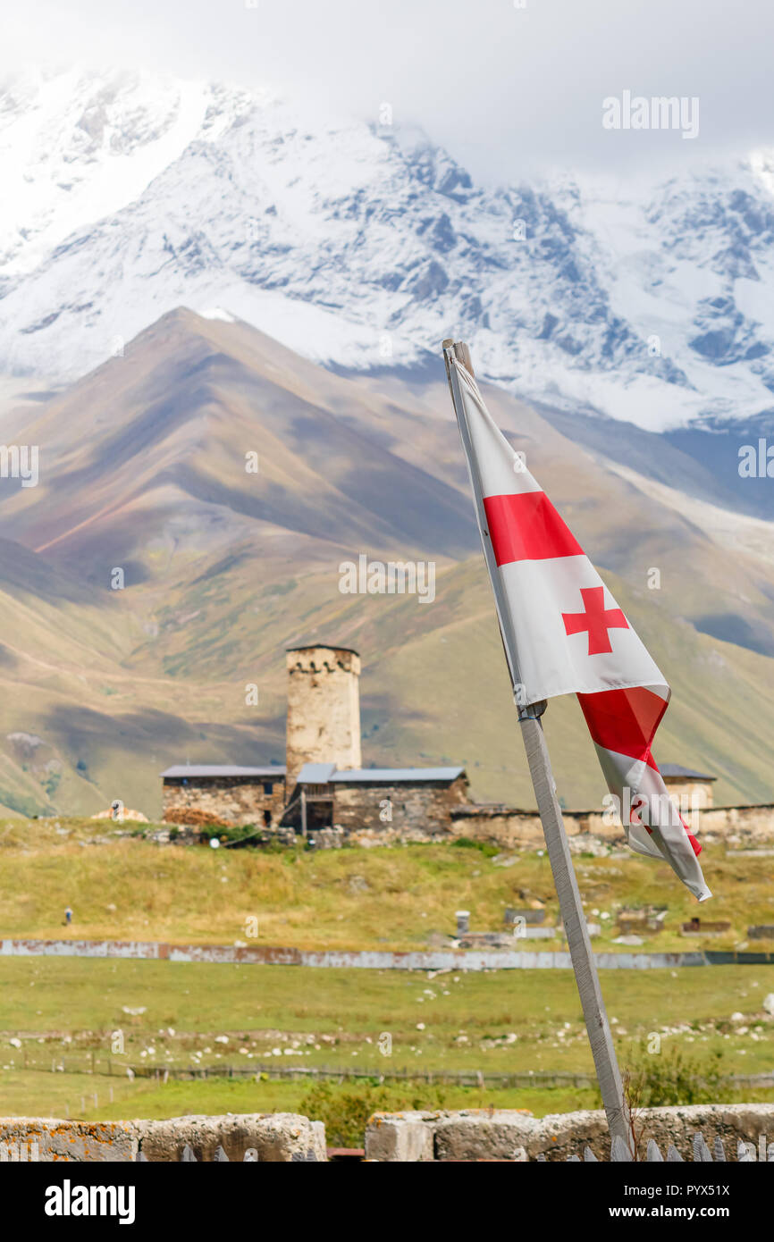 Que enarbola bandera de Georgia con Svan's Tower y montañas en el fondo, Ushguli, Mestia, Svaneti Foto de stock