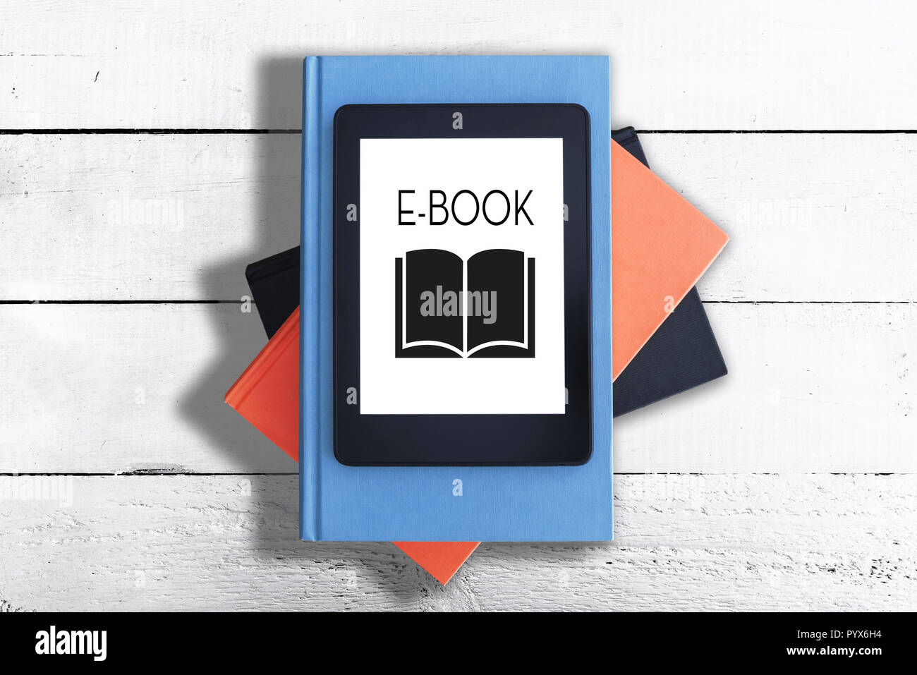 E-reader en la pila de libros contra la mesa de madera rústica blanca Foto de stock
