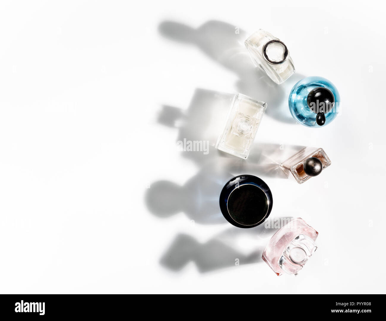 Sombras de frascos de perfume cayendo sobre un fondo blanco. Vista desde arriba. Foto de stock