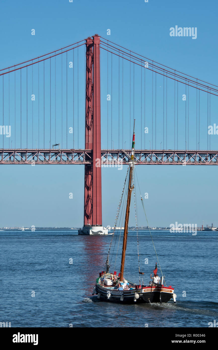 Barcos de excursión en el río Tajo (Rio Tejo) con el puente 25 de abril puente colgante, Lisboa, Portugal. Foto de stock